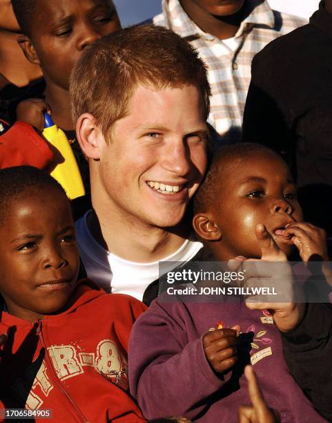 Britain's Prince Harry cuddles children Mutsu and Lintle in the grounds of the Mants'ase children's home, 24 April 2006, while on a return visit to...