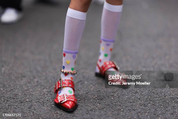 Fashion Week guest is seen wearing white socks with colourful hearts and red leather buckle loafers from GANNI during the Marni Show Spring/Summer...