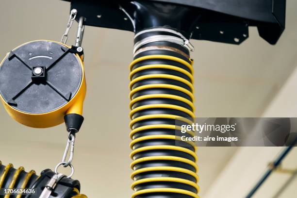 yellow pulley with metal extraction tube in an auto mechanic's shop, low angle view - shock absorber stock pictures, royalty-free photos & images