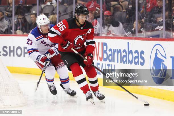 New Jersey Devils center Jack Hughes skates with the puck while being defended by New York Rangers defenseman Adam Fox during a preseason game...