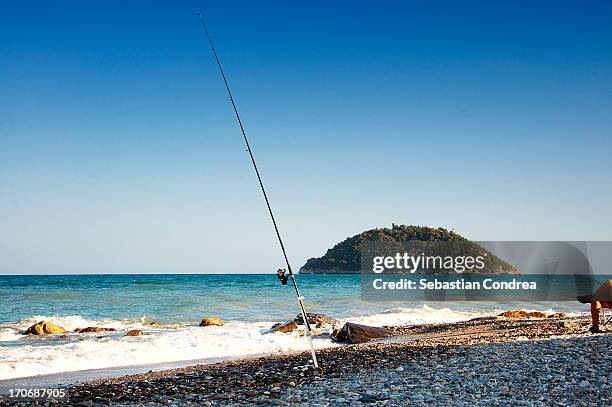 fishing rod, gallinara island in background - angel island stock-fotos und bilder