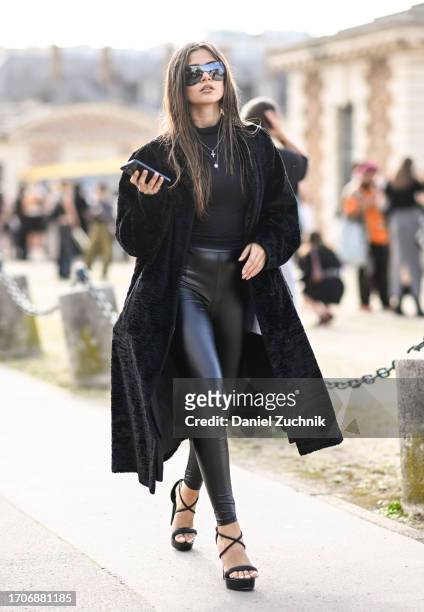 Model is seen wearing a black coat, black top, black leather pants and black strap shoes with black sunglasses outside the Givenchy show during the...