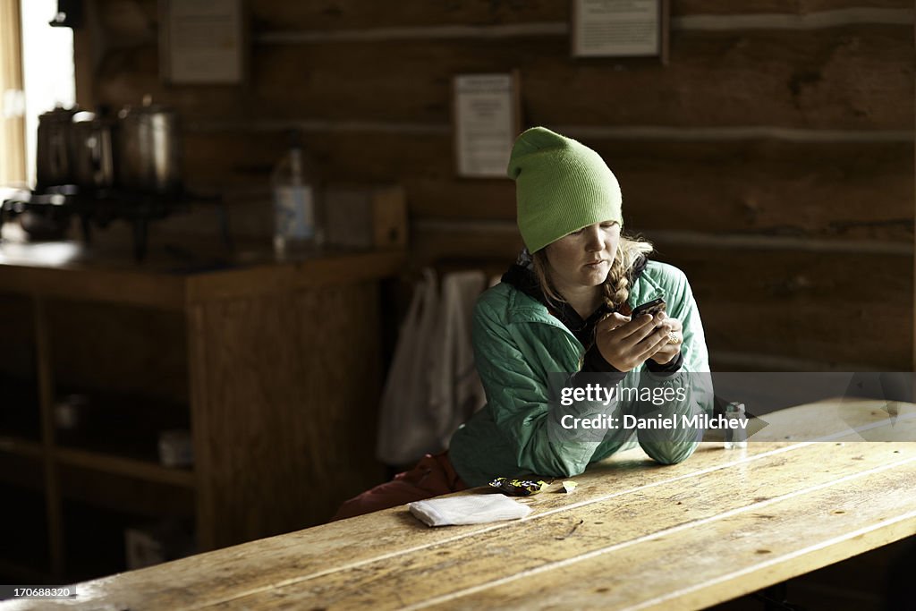 Girl on a smart phone at a mountain hut.