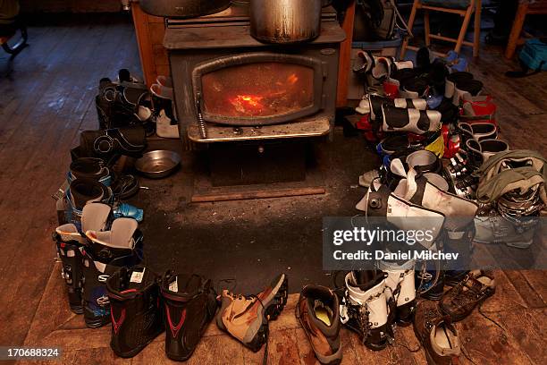 shoes, ski and snowboard boots around a fireplace. - ski hut stock pictures, royalty-free photos & images