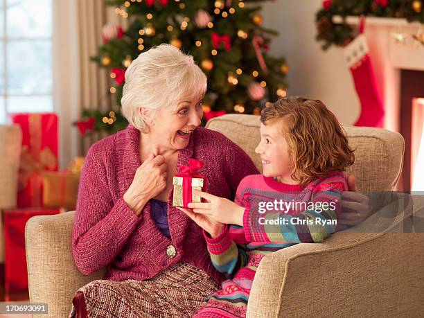 mädchen mit großmutter holding christmas gift - child giving gift stock-fotos und bilder