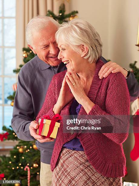 man surprising woman with christmas gift - old man woman christmas stock pictures, royalty-free photos & images