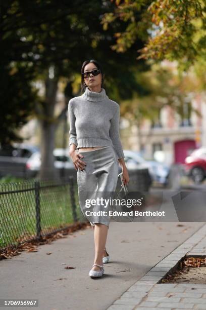 Guest wears sunglasses, a crop top / turtleneck wool knit pullover, an on-knee lustrous shiny / fluffy skirt, a white Prada bag, ballerina shoes,...