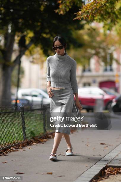 Guest wears sunglasses, a crop top / turtleneck wool knit pullover, an on-knee lustrous shiny / fluffy skirt, a white Prada bag, ballerina shoes,...