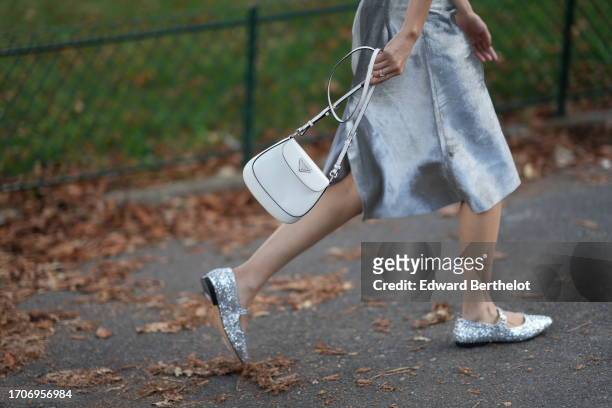Guest wears an on-knee lustrous shiny / fluffy skirt, a white Prada bag, ballerina shoes, outside Christopher Esber, during the Womenswear...