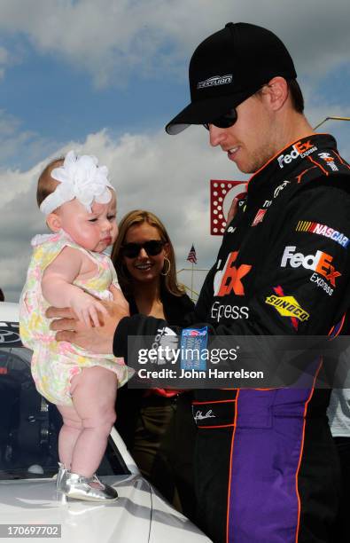 Denny Hamlin, driver of the FedEx Express Toyota, holds his daughter Taylor James Hamlin as his girlfriend Jordan Fish looks on during pre-race...