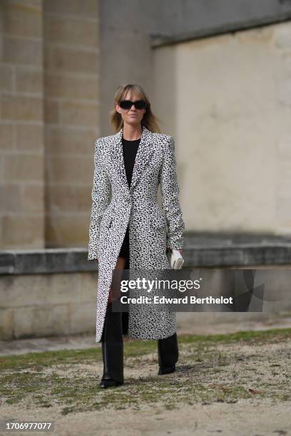 Jeanette Madsen wears sunglasses, a black dress, a black and white leopard print long coat, black knee-high leather boots , a white bag outside...