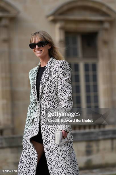 Jeanette Madsen wears sunglasses, a black dress, a black and white leopard print long coat, black knee-high leather boots , a white bag outside...