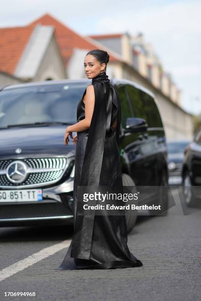 Lena Mahfouf aka Lena Situations wears a black turtleneck leather low-neck sleeveless long dress with cape, high heels / shoes, outside Givenchy,...