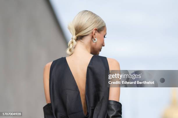 Leonie Hanne wears a sleeveless silk lustrous back nude long dress, a black long gloves, earrings , outside Givenchy, during the Womenswear...