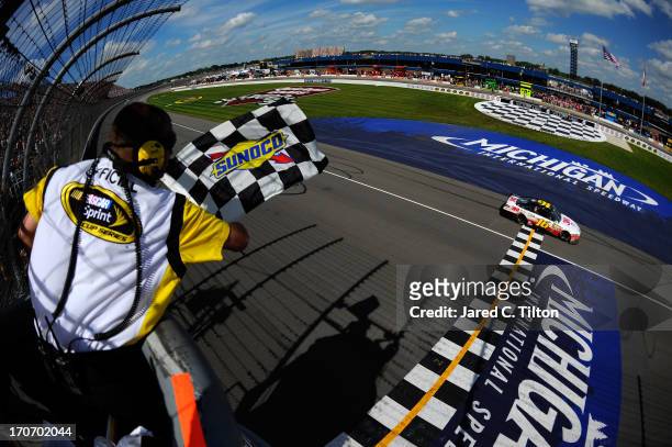Greg Biffle, driver of the 3M/Give Kids a Smile Ford, crosses the finish line to win the NASCAR Sprint Cup Series Quicken Loans 400 at Michigan...