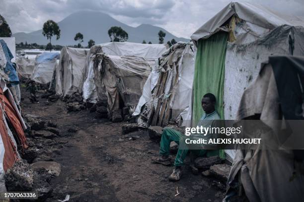 Young man sits in front of his makeshift shelter in the Rusayo IDP camp, home to tens of thousands of war-displaced people, situated at the foot of...