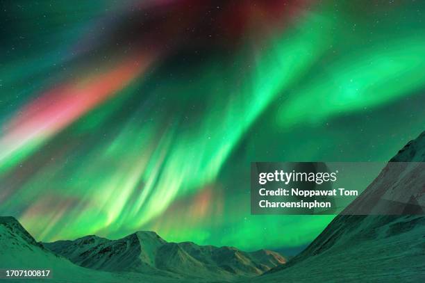 strong geomagnetic aurora borealis (northern lights) dancing over the alaskan peaks near atigun pass along the dalton highway, located to the north of fairbanks, alaska, usa. - aurora borealis stock pictures, royalty-free photos & images