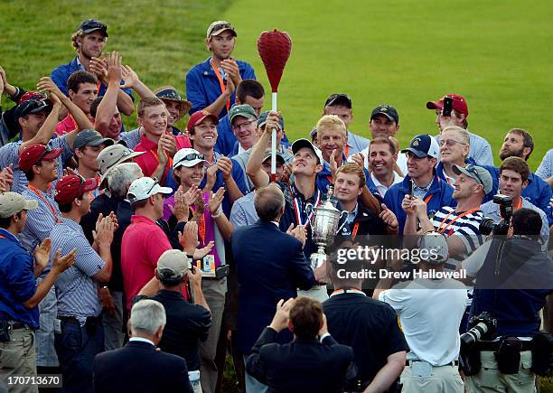 Justin Rose of England celebrates with the U.S. Open trophy admist a group of people while holding a wicker basket flagstick after winning the 113th...