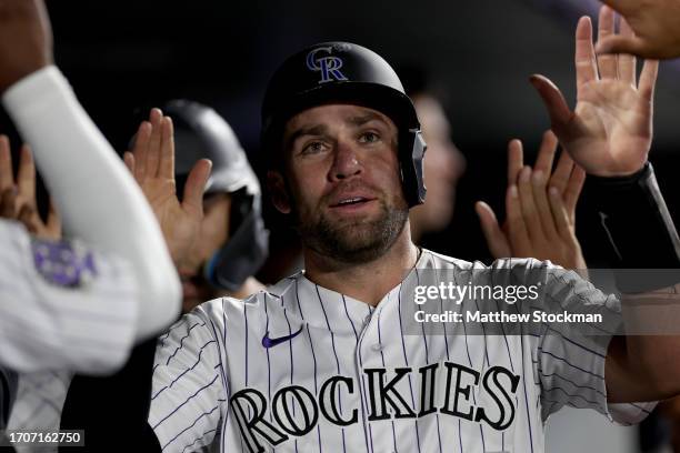 Austin Wynns of the Colorado Rockies celebrates in the dugout after scoring on a Brenton Doyle triple against the Los Angeles Dodgers in the seventh...