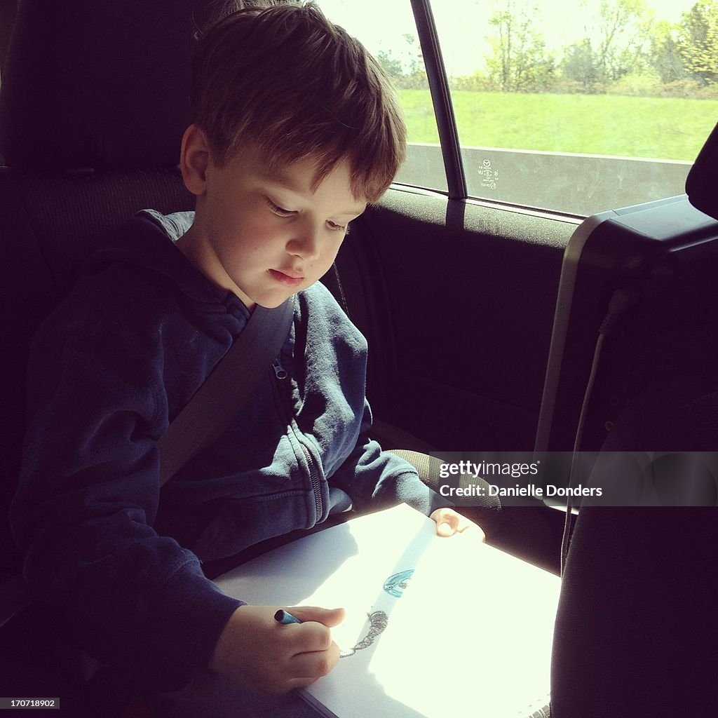 Boy drawing in the car