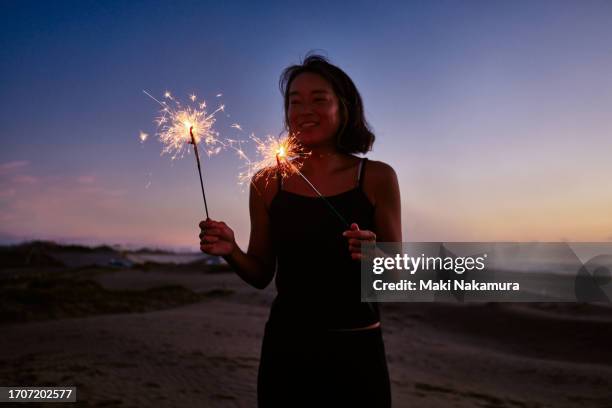 portrait of a woman enjoying fireworks at the beach. - candela magica foto e immagini stock
