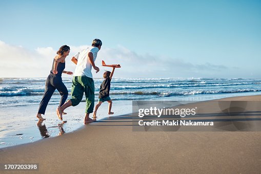 Parents running behind a boy running straight ahead with a model airplane held high in one hand. Parents running behind a boy running straight ahead with a model airplane held high in one hand.