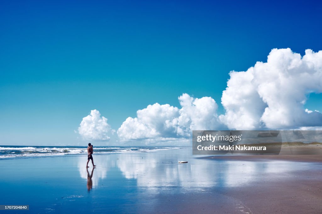 Father walks along the beach with his small son in his arms.