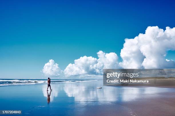 father walks along the beach with his small son in his arms. - beach holiday stock pictures, royalty-free photos & images