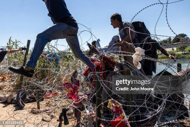 Immigrants cross over razor wire after crossing from Mexico into the United States on September 28, 2023 in Eagle Pass, Texas. A surge of asylum...