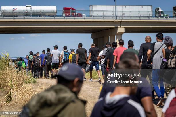 Immigrants walk towards a U.S. Border Patrol checkpoint after crossing the U.S.-Mexico border on September 28, 2023 in Eagle Pass, Texas. A surge of...