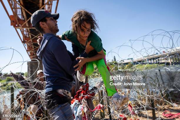 Immigrants cross over razor wire after crossing from Mexico into the United States on September 28, 2023 in Eagle Pass, Texas. A surge of asylum...