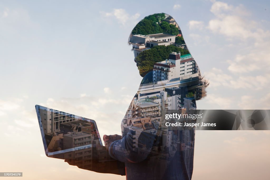 Composite of woman using laptop and cityscape