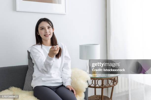 asian woman on sofa watching a tv - film screening room stock pictures, royalty-free photos & images