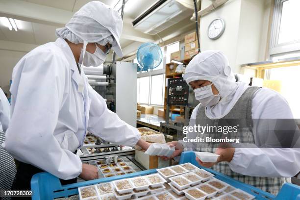 Employees arrange sachets of seasoning sauce and mustard onto polystyrene trays of fermented soybeans, known as natto, at the Matsushita Shoten Y.K....