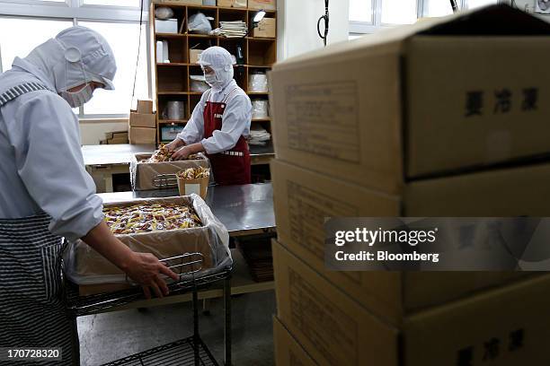 Employees open boxes filled with sachets of seasoning sauce and mustard to accompany packets of fermented soybeans, known as natto, at the Matsushita...