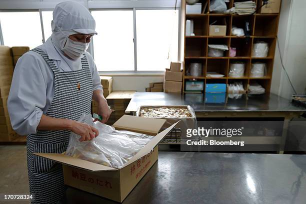 An employee opens a box filled with sachets of seasoning sauce and mustard to accompany packets of fermented soybeans, known as natto, at the...