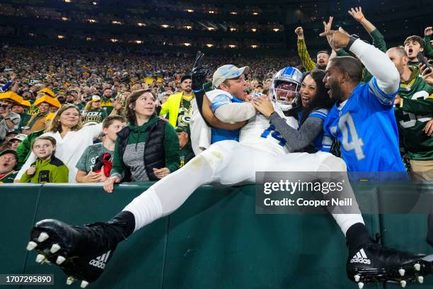 Amon-Ra St. Brown of the Detroit Lions leaps into the crowd to celebrate during an NFL football game at Lambeau Field on September 28, 2023 in Green...