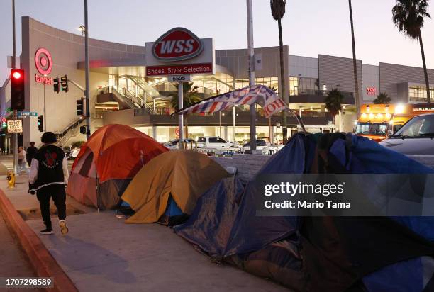 Person walks past a homeless encampment near a Target store on September 28, 2023 in Los Angeles, California. State and local lawmakers, both...