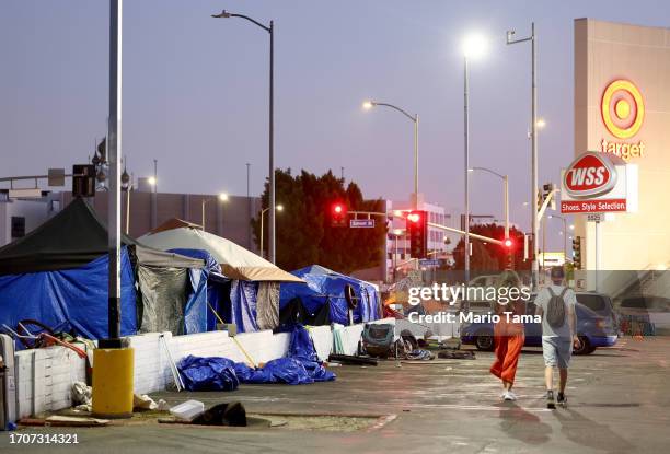 People walk past a homeless encampment near a Target store on September 28, 2023 in Los Angeles, California. State and local lawmakers, both...