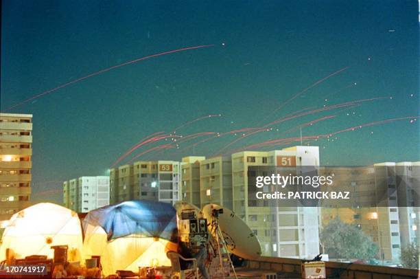 Red traces of anti-aircraft machine gun fire sear across the Baghdad's skyline as the set up of TV crews can be seen on the roof of the press center...