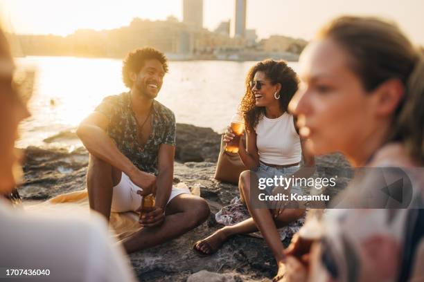 a group of people gathered on the beach to spend the afternoon together - golden hour beach stock pictures, royalty-free photos & images