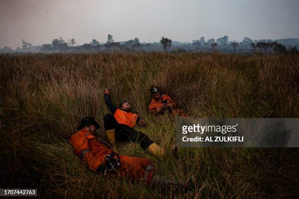 Picture taken on October 4 shows firefighters taking a break as they try to extinguish a peatland fire in Palembang, South Sumatra.