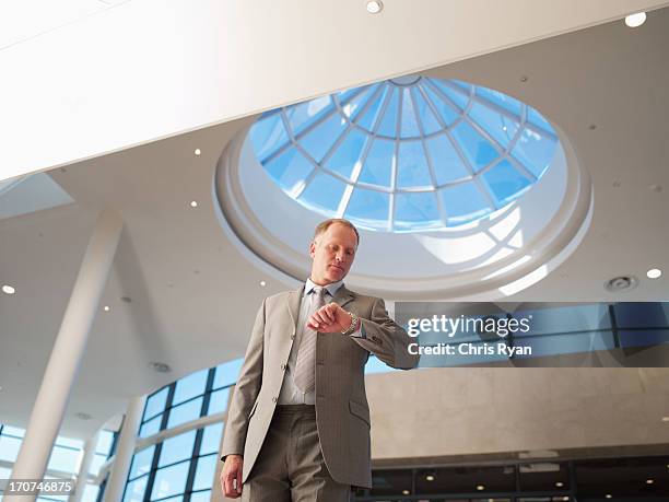 businessman checking wristwatch - skylight stock pictures, royalty-free photos & images