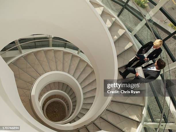 business people talking on circular staircase - stairs business stockfoto's en -beelden