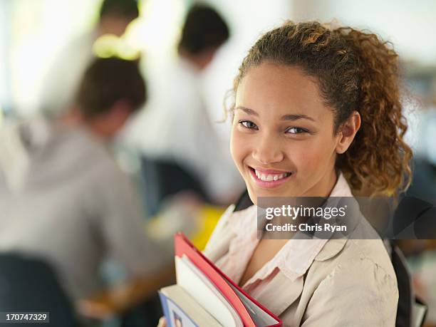 college student sonriente sosteniendo libros - 18 19 años fotografías e imágenes de stock