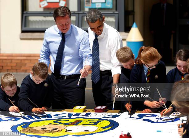 President Barack Obama, fourth left, and British Prime Minister David Cameron, third left, help students as they work on a school project about the...