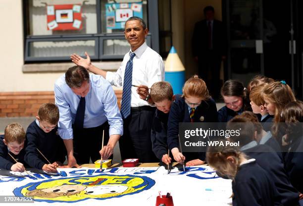 President Barack Obama, fourth left, reacts as the sun comes out as he works alongside British Prime Minister David Cameron, third left, helping...