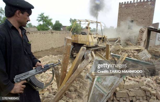 Paramilitary trooper takes his position as a bulldozer raises different premises to the ground during a massive anti-terrorism and anti-smuggling...