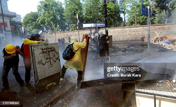 Anti-government protesters protect themselves from water cannon fired by police in the Kurtulus district on June 16, 2013 in Istanbul, Turkey....