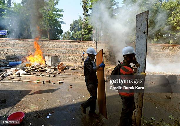 Anti-government protesters stand beside burning barricades as they prepare to confront police using water cannon in Kurtulus district on June 16,...